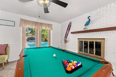 a pool table in a living room with a pool ball at Flirty Flamingo with Private Heated Pool, Game Room, and AMAZING Covered Outdoor Living in Panama City Beach