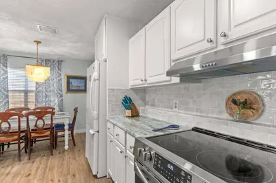 a kitchen with white cabinets and a stove top oven at Fanta Sea - Private Seasonal Hot Tub, Game Room, Walk to Beach, Pets OK, & More! in Panama City Beach
