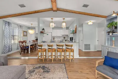 a kitchen and living room with a table and chairs at Fanta Sea - Private Seasonal Hot Tub, Game Room, Walk to Beach, Pets OK, & More! in Panama City Beach