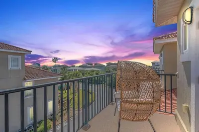 a wicker chair sitting on a balcony with a sunset at Bella Costa 160- Sandy Feet Retreat in Panama City Beach