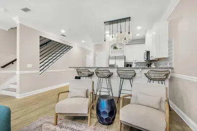 a white kitchen with a bar and stools at Bella Costa 160- Sandy Feet Retreat in Panama City Beach