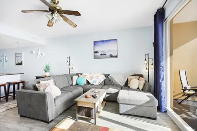 a living room with a gray couch and a table at Emerald Chic BeachFront 2 bdr apt 4 beach seats and a cannope on us in Panama City Beach