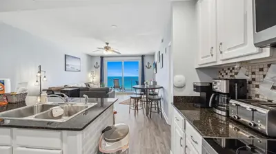 a kitchen and living room with a view of the ocean at Emerald Chic BeachFront 2 bdr apt 4 beach seats and a cannope on us in Panama City Beach