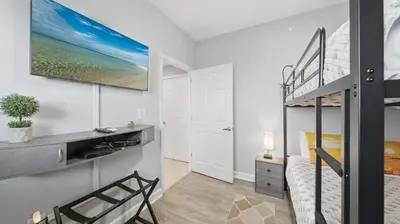 a bedroom with a bunk bed and a desk at Emerald Chic BeachFront 2 bdr apt 4 beach seats and a cannope on us in Panama City Beach