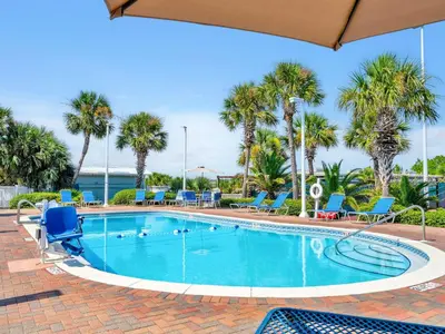 a swimming pool with blue chairs and palm trees at Pinnacle Port A-910 in Panama City Beach