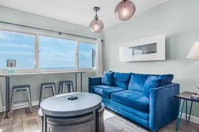 a living room with a blue couch and a table at Pinnacle Port A-910 in Panama City Beach