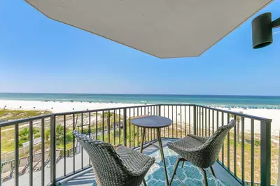 a balcony with two chairs and a table and the beach at Sunbird 404E in Panama City Beach