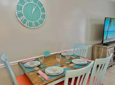a dining room table with a clock on the wall at Beach Haven - Seasonal Hot Tub, Fire Pit, BBQ, 700 Feet to Beach, Central PCB, FREE Daily Activities, & More! in Panama City Beach