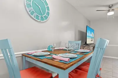 a dining room with a table and a clock on the wall at Beach Haven - Seasonal Hot Tub, Fire Pit, BBQ, 700 Feet to Beach, Central PCB, FREE Daily Activities, & More! in Panama City Beach