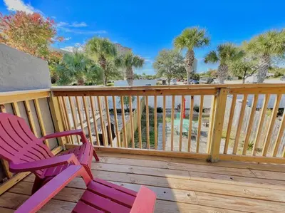 two chairs sitting on a deck with palm trees at Beach Haven - Seasonal Hot Tub, Fire Pit, BBQ, 700 Feet to Beach, Central PCB, FREE Daily Activities, & More! in Panama City Beach