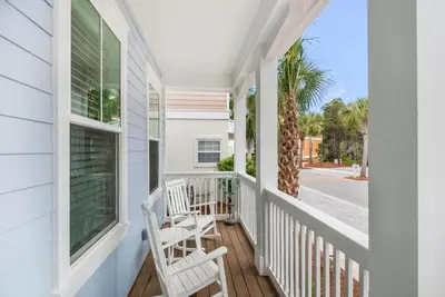 a porch with two chairs and a palm tree at The Eagles Nest in Rosemary Beach