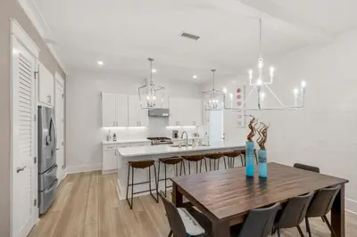 a white kitchen with a wooden table and chairs at The Eagles Nest in Rosemary Beach