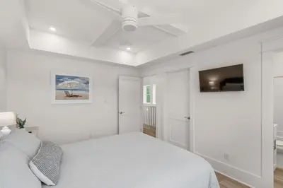 a white bedroom with a bed and a ceiling fan at The Eagles Nest in Rosemary Beach