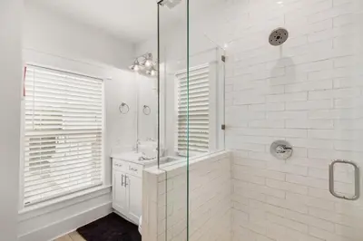 a white bathroom with a shower and a sink at The Eagles Nest in Rosemary Beach