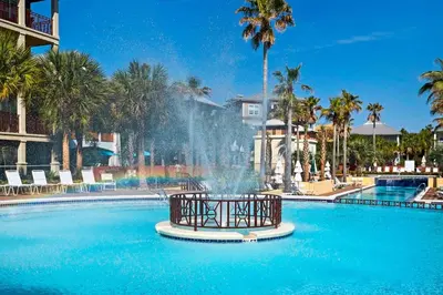 a fountain in the middle of a pool with palm trees at The Eagles Nest in Rosemary Beach