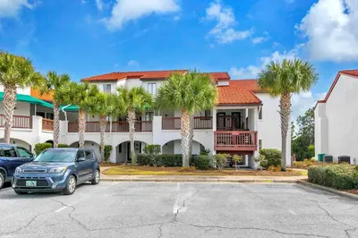 a car parked in front of a building with palm trees at St Thomas Square Villa 414 in Panama City Beach