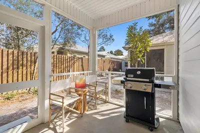 a screened in porch with a grill and a table and chairs at 30A Beach House - Coconut Cottage by Panhandle Getaways in Santa Rosa Beach