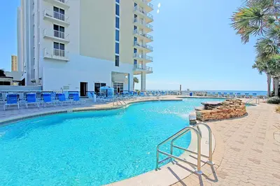 a swimming pool with blue chairs and a building at Majestic Beach Towers 1-407 in Panama City Beach