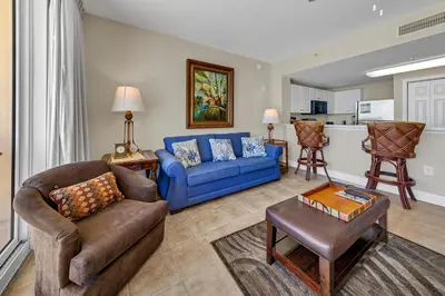 a living room with blue couches and a kitchen at Majestic Beach Towers 1-407 in Panama City Beach