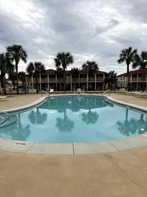 a large blue swimming pool with palm trees in the background at Lazy Palm 4 Pools Short Walk To Beach! Sleeps 5! in Panama City Beach