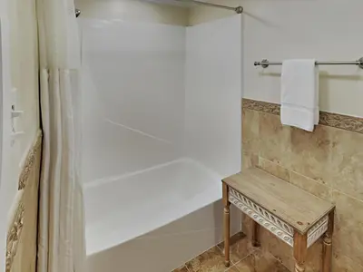 a bathroom with a shower with a bench and a shower curtain at Edgewater Leeward #500 in Panama City Beach