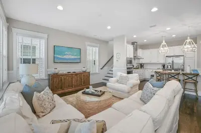 a living room with white furniture and a kitchen at Beach Bliss 30A in Destin