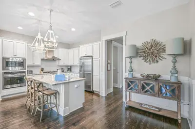 a kitchen with white cabinets and a island with bar stools at Beach Bliss 30A in Destin