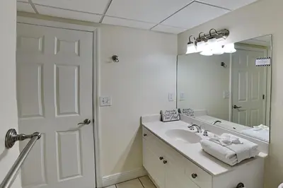 a white bathroom with a sink and a mirror at Emerald Beach #630 in Panama City Beach