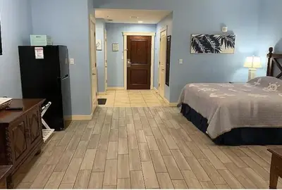 a bedroom with a bed and a refrigerator in it at Origin at Seahaven in Panama City Beach