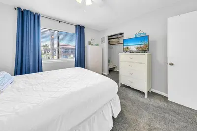 a bedroom with a white bed and a dresser and a window at Portside K5 in Panama City Beach