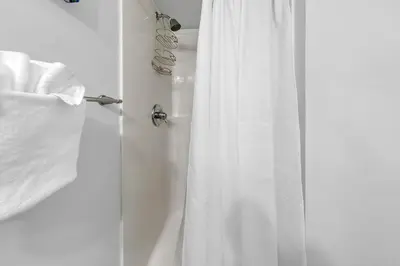 a shower with a white shower curtain in a bathroom at Portside K5 in Panama City Beach