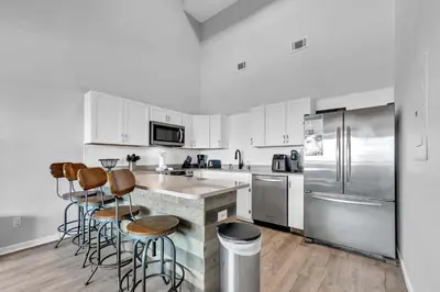 a kitchen with white cabinets and bar stools at Horizon South 54-303 in Panama City Beach