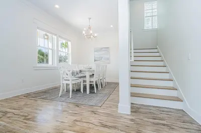 a dining room with a table and chairs and a staircase at Blue Dream in Santa Rosa Beach