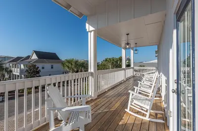 a porch with white chairs on a house at Blue Dream in Santa Rosa Beach