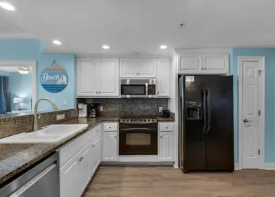 a kitchen with white cabinets and a black refrigerator at Treasure Island 2005 Beach Front in Panama City Beach