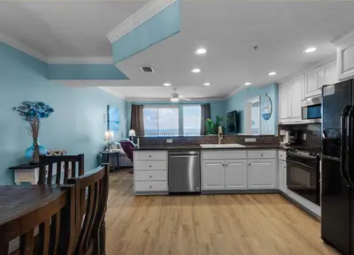 a kitchen with white cabinets and blue walls at Treasure Island 2005 Beach Front in Panama City Beach