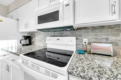 a kitchen with white cabinets and a stove top oven at Cassine Gardens 273- Kwitcherbeachin' in Santa Rosa Beach
