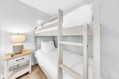 a bedroom with a bunk bed and a night stand with a desk at Cassine Gardens 273- Kwitcherbeachin' in Santa Rosa Beach