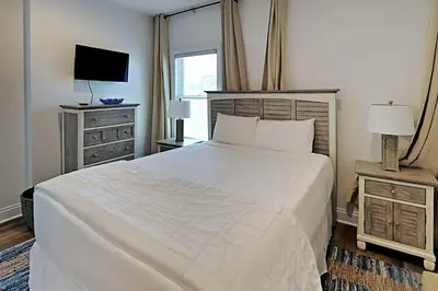 a bedroom with a large white bed and a television at Bonita Point Condo II #214E in Panama City Beach