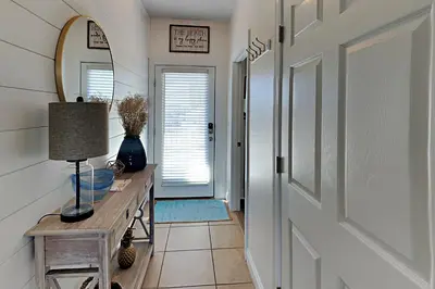 a hallway with a door and a table and a mirror at Bonita Point Condo II #214E in Panama City Beach