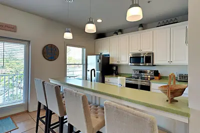 a kitchen with white cabinets and a counter with chairs at Bonita Point Condo II #214E in Panama City Beach
