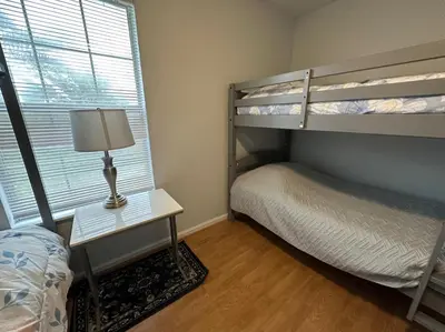 a bedroom with two bunk beds and a table with a lamp at Beautiful House Sleeps 12 - Hot Tub - Breakfast - Walk to Beach in Panama City Beach