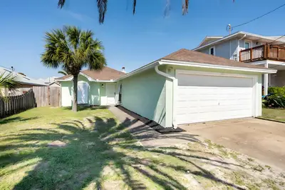 a house with a white garage and a palm tree at Beautiful House Sleeps 12 - Hot Tub - Breakfast - Walk to Beach in Panama City Beach
