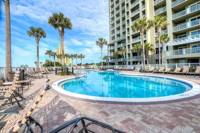 a swimming pool with palm trees and a building at Grand Panama 2-307 in Panama City Beach