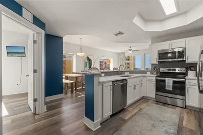 a kitchen with white cabinets and blue walls at New Calypso Beach Resort Corner Unit Sleeps 8! by Dolce Vita Getaways PCB in Panama City Beach