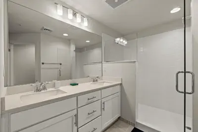 a white bathroom with two sinks and a shower at New Calypso Beach Resort Corner Unit Sleeps 8! by Dolce Vita Getaways PCB in Panama City Beach