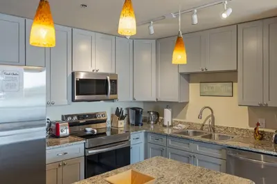 a kitchen with white cabinets and stainless steel appliances at Stunning Resort Low Floor Condo! Sleeps 8! Steps 2 Beach & Restaurants! by Dolce Vita Getaways PCB in Panama City Beach