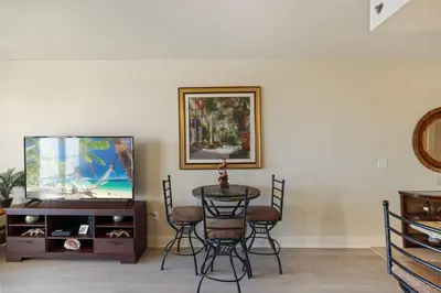 a living room with a tv and a table and chairs at Stunning Resort Low Floor Condo! Sleeps 8! Steps 2 Beach & Restaurants! by Dolce Vita Getaways PCB in Panama City Beach