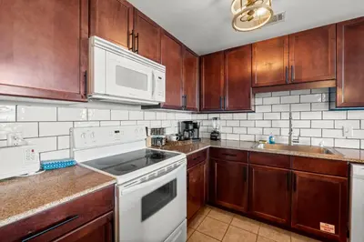 a kitchen with wooden cabinets and white appliances at Stunning Views! located Steps 2 Beach, Restaurants & Shops! by Dolce Vita Getaways PCB in Panama City Beach