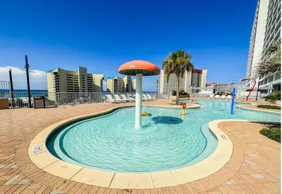 a fountain in the middle of a pool with an umbrella in the water at Stunning Views! located Steps 2 Beach, Restaurants & Shops! by Dolce Vita Getaways PCB in Panama City Beach